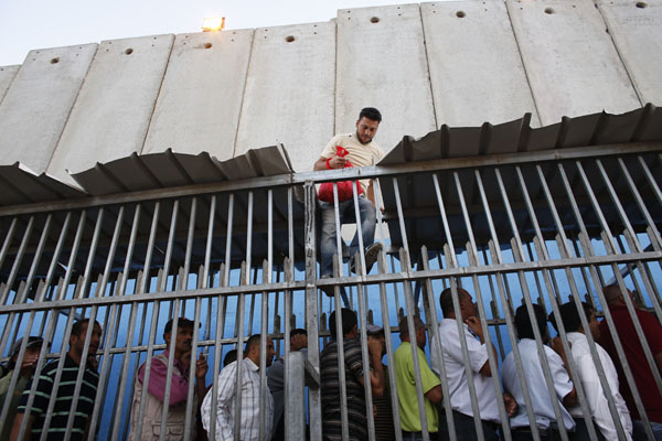 Palestinians wait to cross into Jerusalem at an Israeli checkpoint in Bethlehem
