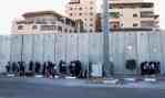 Palestinian schoolgirls wait for buses in the shadow of the Israeli wall, inside the Shua’fat refugee camp near Jerusalem. Photograph Jim&nbsp;Hollande